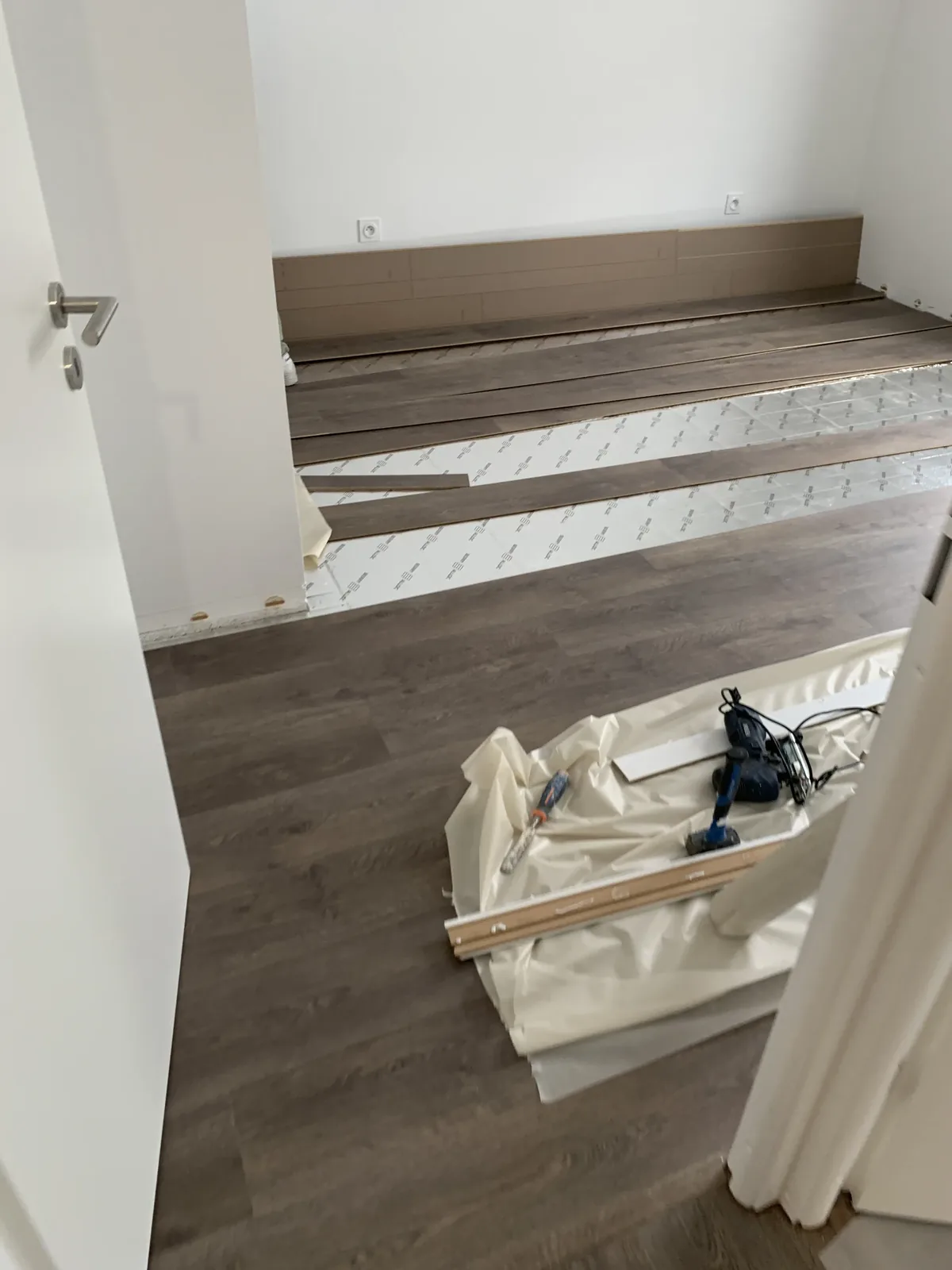 Pose d'un revêtement de sol souple en lames dans une pièce en cours de rénovation.